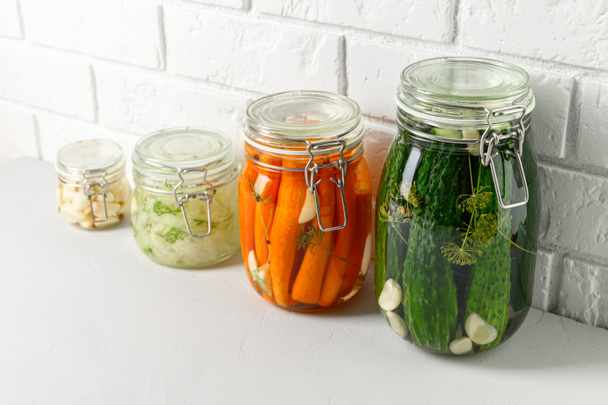 Comida vegetariana saudável. Vegetais fermentados caseiros pepinos, cenouras, repolho e alho em frascos de vidro
. - Foto, Imagem