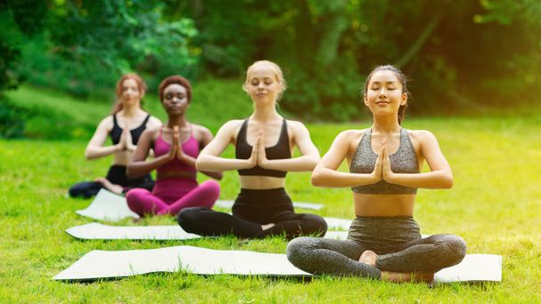Békés, változatos lányok meditálnak a szabadtéri jóga edzés alatt reggel - Fotó, kép