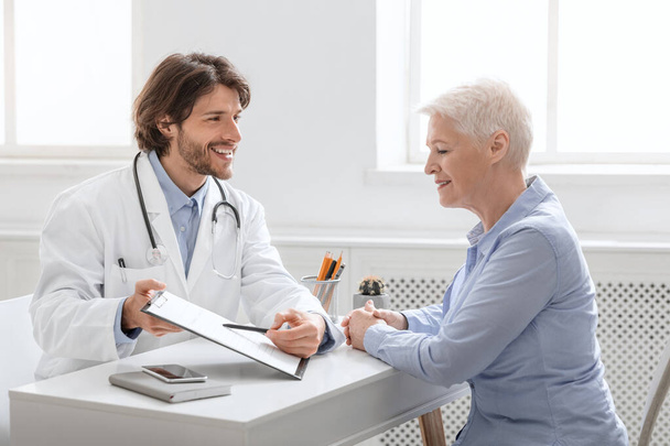 Fröhlicher Arzt zeigt Seniorin gute Testergebnisse - Foto, Bild