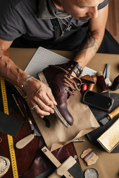 Close up of shoe maker hands producing boots in his leather workshop - Foto, Imagen