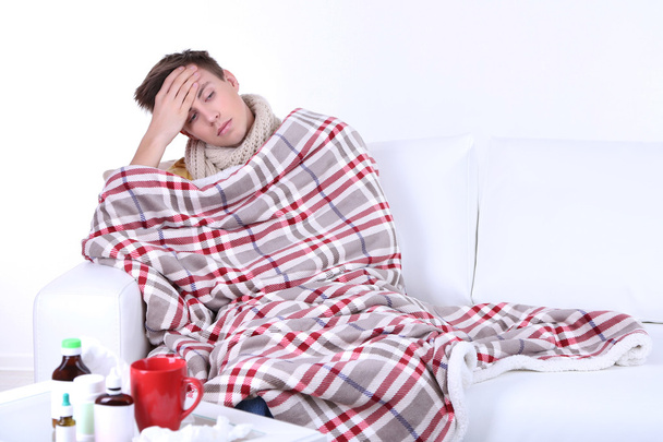 Guy wrapped in plaid sitting on sofa is ill - Foto, afbeelding