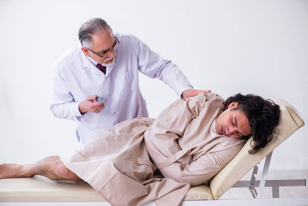 Médico psiquiatra anciano examinando paciente joven
 - Foto, Imagen