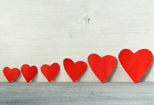 Dia dos namorados fundo, corações vermelhos em uma linha em um fundo de madeira leve
 - Foto, Imagem