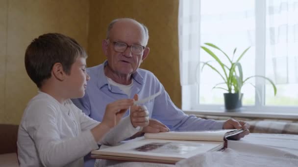 Beziehungsfamilie, freudiges männliches Kind, zusammen mit einem älteren Mann, wird Erinnerungen aus einem Fotoalbum erben - Filmmaterial, Video