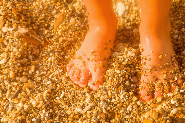 Summer holiday and leisure concept. Children's feet on the sand by the sea. - Photo, Image