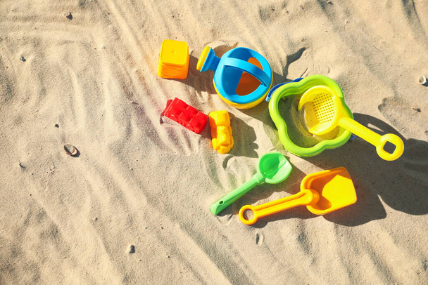Different child plastic toys on sandy beach, flat lay. Space for text - 写真・画像