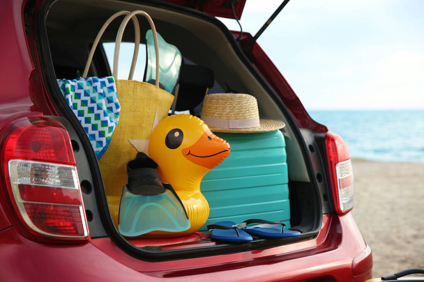 Red car with luggage on beach, closeup. Summer vacation trip - Foto, imagen