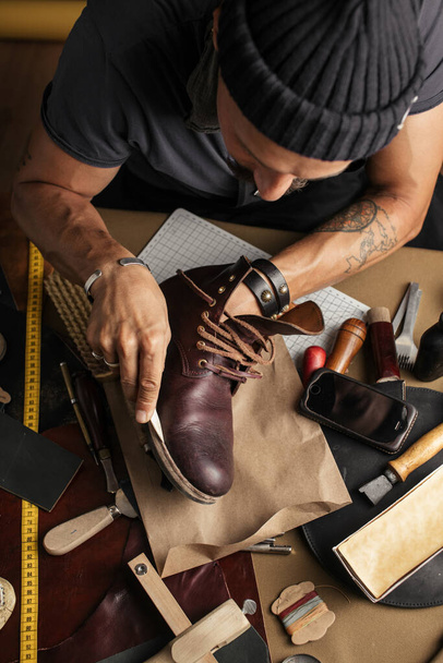 Close up of shoe maker hands producing boots in his leather workshop - Foto, Imagem