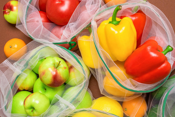 再利用可能な環境に優しいメッシュバッグに新鮮でジューシーな果物や野菜。プラスチックフリー、廃棄物ゼロ、持続可能な生活の概念。再利用可能。最上階だ。クローズアップビュー. - 写真・画像