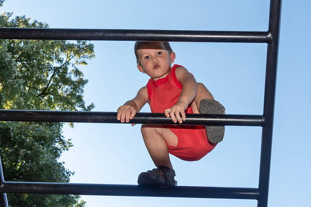 A kisfiú magas akadályokba ütközik a játszótéren. - Fotó, kép