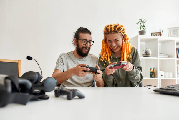 Man and woman using, discussing game controller joystick. Young male and female technology blogger recording video blog or vlog about new gadgets at home - Zdjęcie, obraz