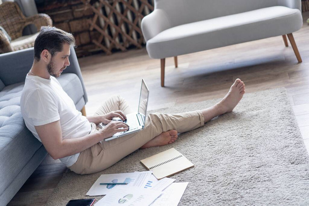Férfi dolgozik laptop számítógép ül a padlón a napló és a hivatalos papírok otthon - Fotó, kép