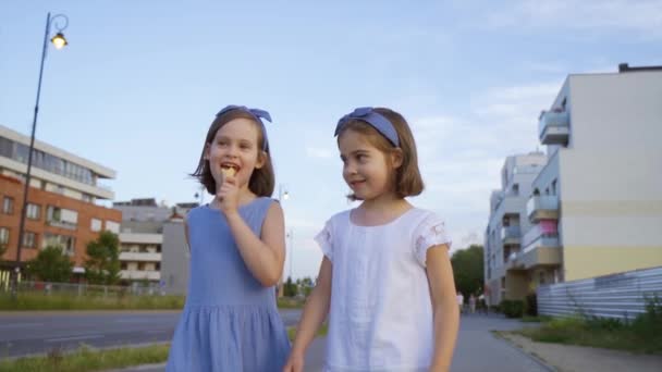 Két aranyos kislány sétálgat a városban és jégkrémet eszik. - Felvétel, videó