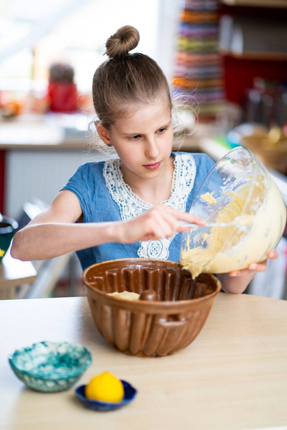 Genç kız, hazırlığı kolay ve sağlıklı, ev yapımı Paskalya pastası yapıyor. Hamuru eski bir seramik pişirme kalıbının içine koyuyor.. - Fotoğraf, Görsel