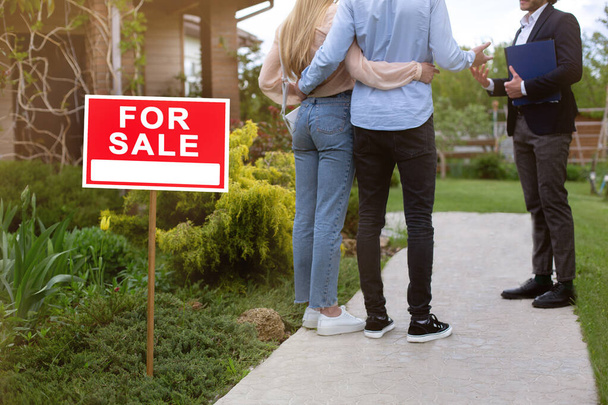 Onherkenbaar jong stel met makelaar op zoek naar residentieel vastgoed te koop, buiten - Foto, afbeelding