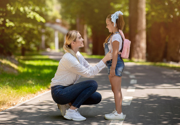 Мама и дочь разговаривают, гуляя в городском парке - Фото, изображение
