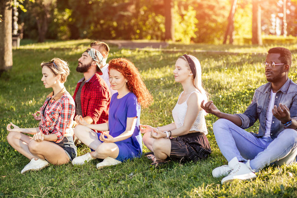 Group of adult friends meditating while practicing yoga outside in park. - Fotó, kép