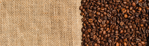 vista superior de granos de café tostados en tela de saco, plano panorámico - Foto, Imagen