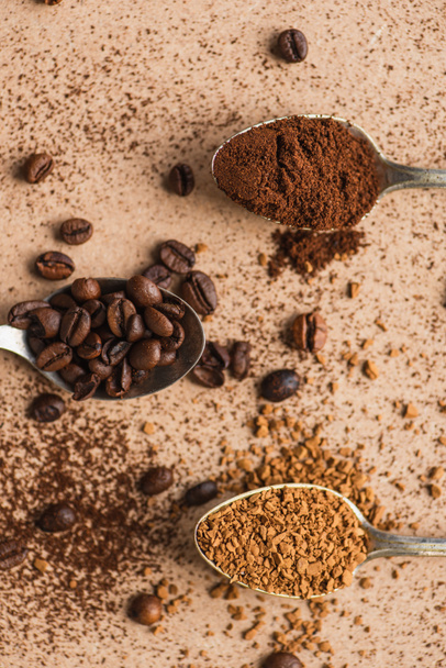 top view of ground, instant coffee and beans in spoons on beige surface - Fotó, kép