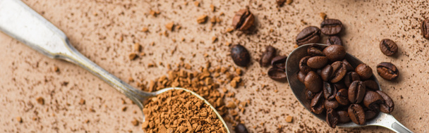 vrchní pohled na instantní kávu a fazole v lžičkách na béžovém povrchu, panoramatický záběr - Fotografie, Obrázek