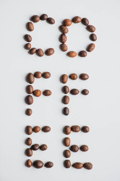top view of coffee lettering made of beans on white surface - Valokuva, kuva