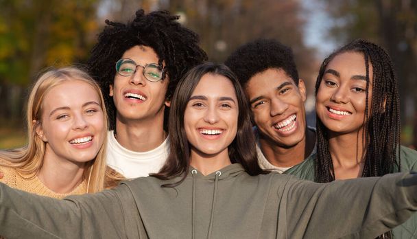 Sonriente adolescente amigos tomando selfie mientras caminando en parque - Foto, imagen