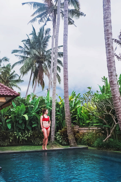 Young woman in red swimsuit standing neat the beautiful swiming pool - Foto, immagini
