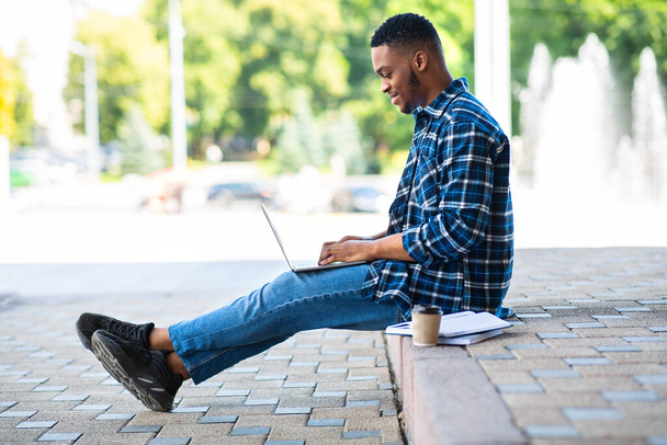 A tanuló laptopot használ, a határon ül a városban - Fotó, kép