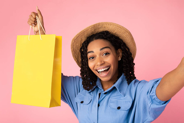 ショッピングセルフィーを作る黒女性ピンクの背景に袋を保持 - 写真・画像