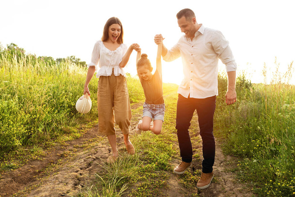 Szczęśliwi rodzice i dziecko spacerujące razem na letnim polu - Zdjęcie, obraz