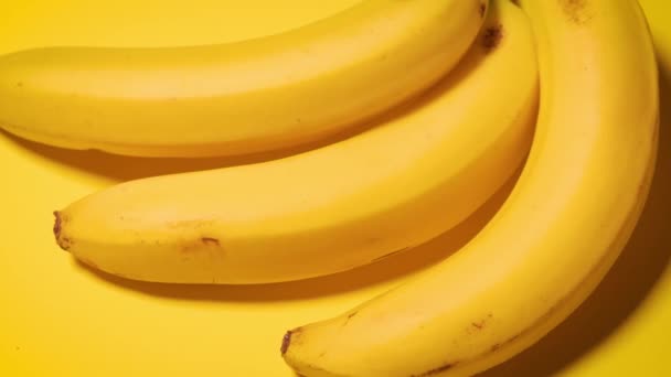 tuoreet banaanit keltaisella minimalistisella pohjalla - Materiaali, video