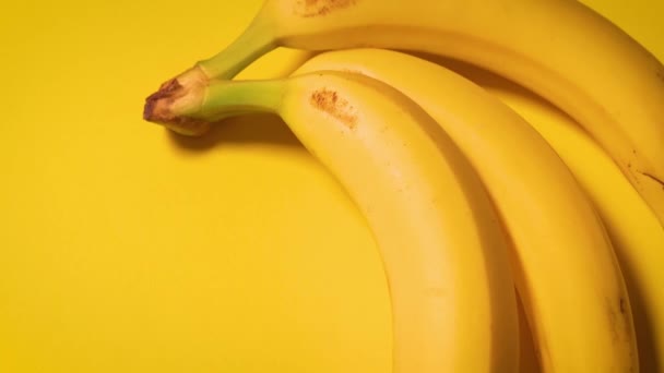 świeże banany na żółtym minimalistycznym tle - Materiał filmowy, wideo