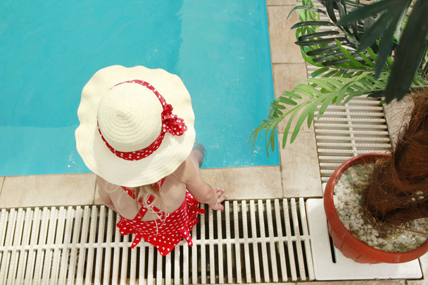 little girl in a hat floating in the pool - Fotoğraf, Görsel