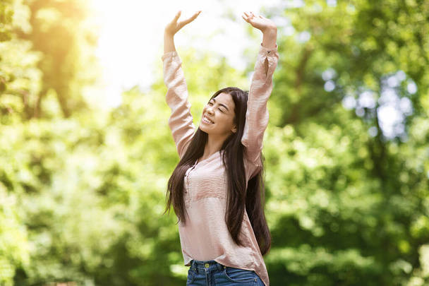 Svoboda. Happy asijské dívka relaxační a těší slunečný den v městském parku - Fotografie, Obrázek