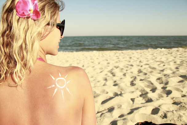 of sun cream on the female back on the beach - Photo, Image