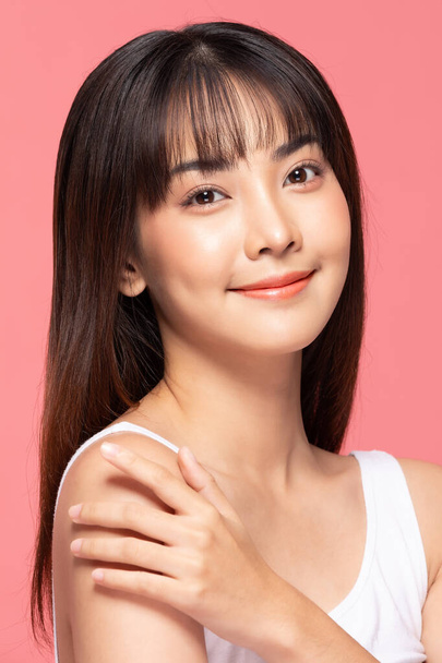 Young Beautiful Asian woman smile touching shoulder with clean and fresh skin Happiness and cheerful with positive emotional,isolated on pink background,Beauty Cosmetics and spa Treatment Concept - Фото, зображення
