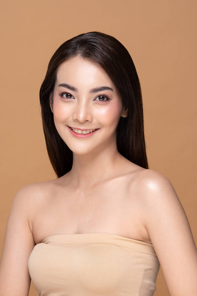 Beautiful Asian woman looking at camera smile with clean and fresh skin Happiness and cheerful with positive emotional,isolated on Beige background,Beauty Cosmetics and spa Facial treatment Concept - Foto, imagen