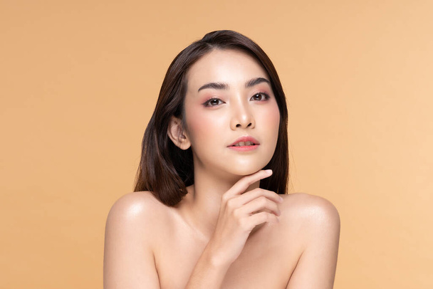 Beautiful Asian woman touching chin smile with clean and fresh skin Happiness and cheerful with positive emotional,isolated on Beige background,Beauty Cosmetics and spa Facial treatment Concept - Zdjęcie, obraz