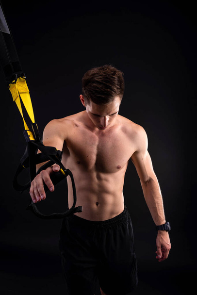 Athletic muscular man doing exercises on trx loops. Body-building. Active lifestyle. - Fotó, kép
