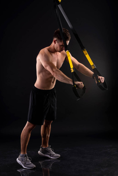 Athletic muscular man doing exercises on trx loops. Body-building. Active lifestyle. - Fotoğraf, Görsel