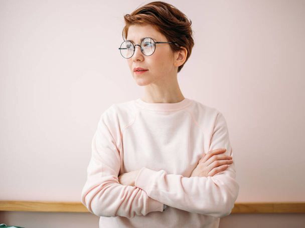 Portrait of middle-aged woman wearing eyeglasses on pink background in home - Φωτογραφία, εικόνα