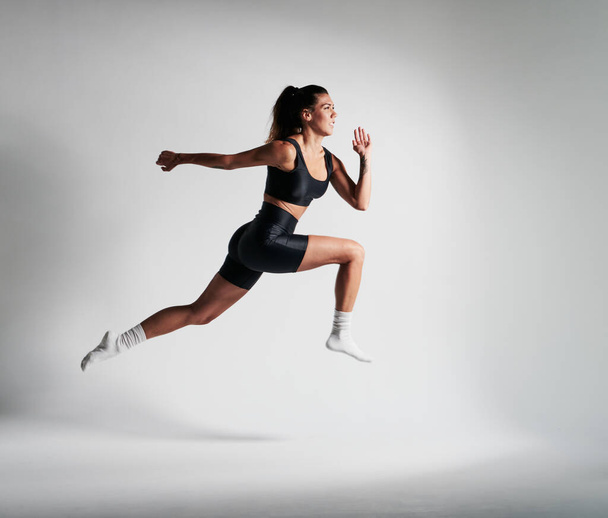 fitness meisje gekleed in zwart, het doen van een grote sprong - Foto, afbeelding