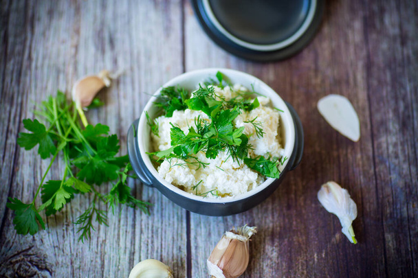 salted homemade cottage cheese with garlic and herbs in a bowl on a wooden table - Photo, image