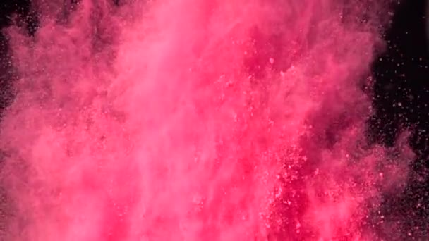 Super slow motion explosie van kleurrijk rood poeder op donkere geïsoleerde achtergrond. Stukjes poeder vliegen omhoog en mengen met de rook. - Video