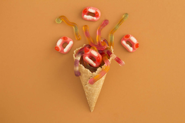 Ice cream cone with candy for Halloween on orange surface. Top view. Copy space. - Foto, Bild
