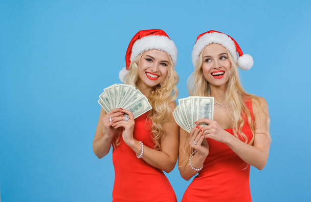 Twin sisters rejoice holding a lot of money in their hands. Happy girls. - 写真・画像