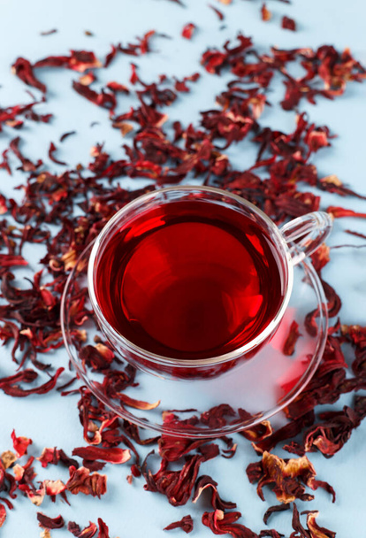 Zdrowa herbata hibiskusa w przezroczystej filiżance na niebieskim tle przestrzeń kopiowania - Zdjęcie, obraz