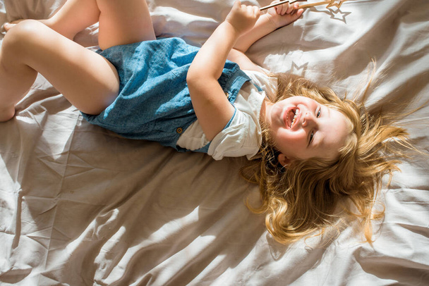 Cheerful baby laughing.A cheerful girl lies on the bed and screams with joy. - Foto, imagen