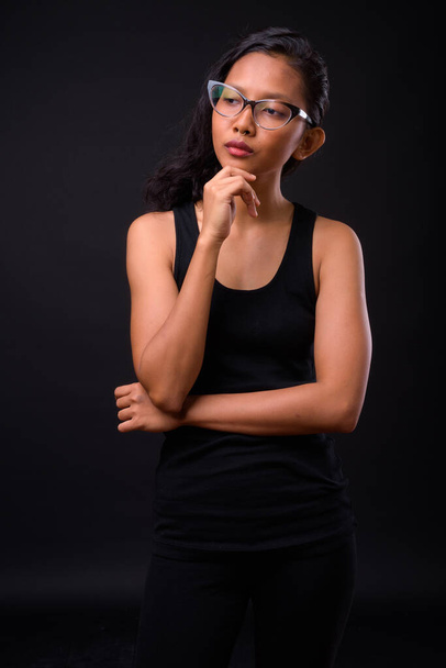 Estudio disparo de joven hermosa mujer asiática con anillo en la nariz sobre fondo negro - Foto, Imagen