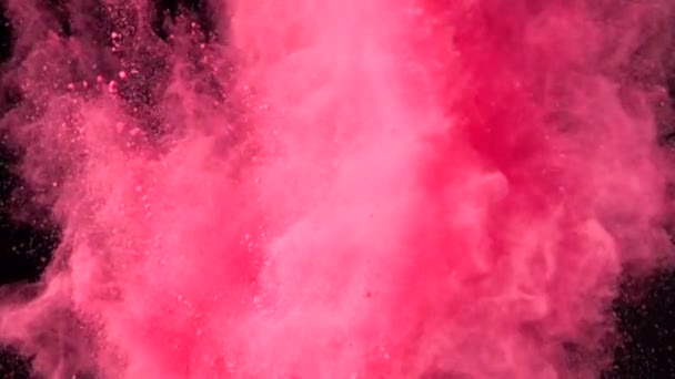 Explosión en cámara súper lenta de colorido polvo rojo sobre fondo oscuro aislado. Los bultos de polvo vuelan hacia arriba y se mezclan con el humo. - Imágenes, Vídeo